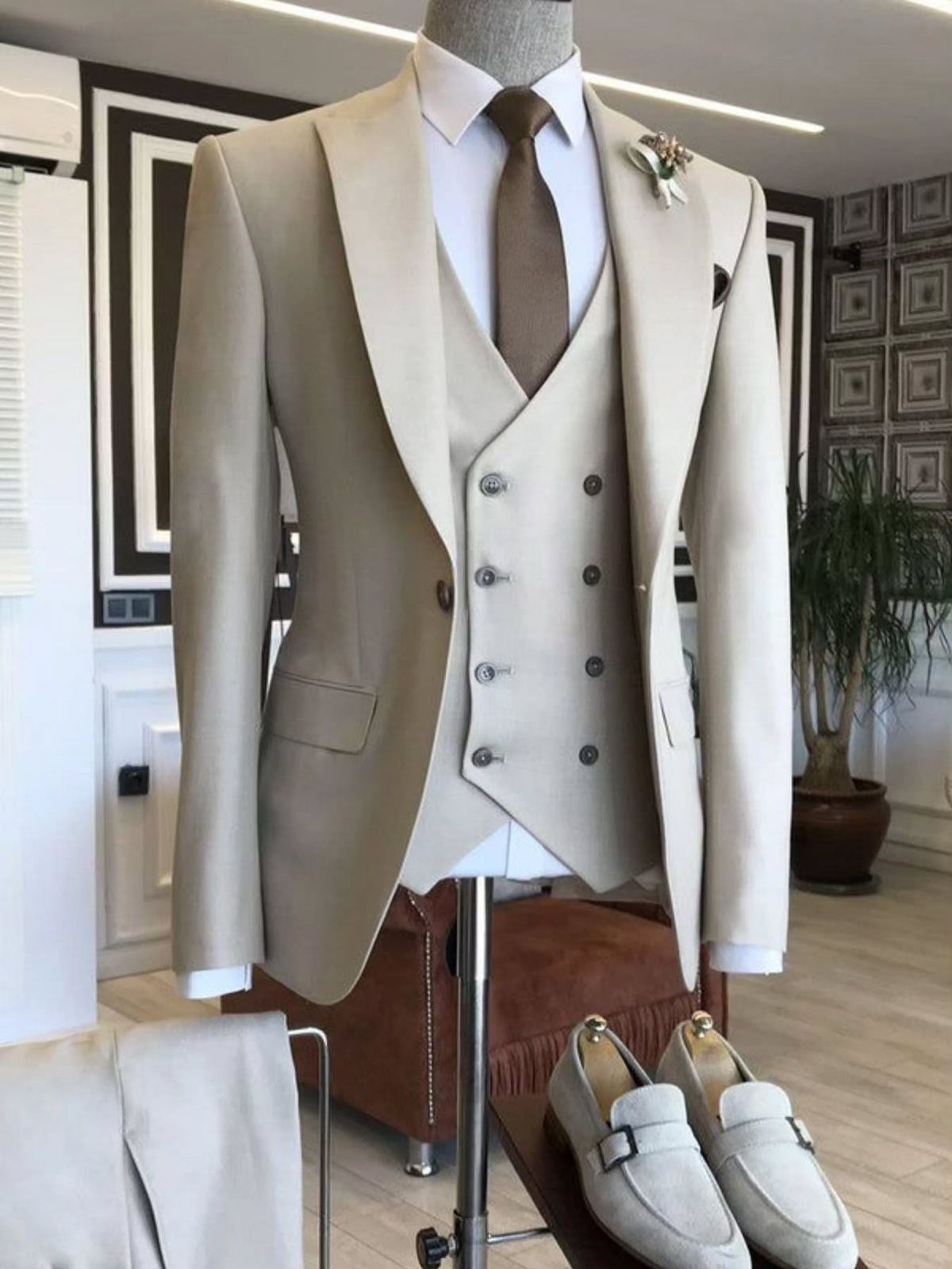 Beige three-piece suit with a double-breasted waistcoat displayed on a mannequin with loafers.