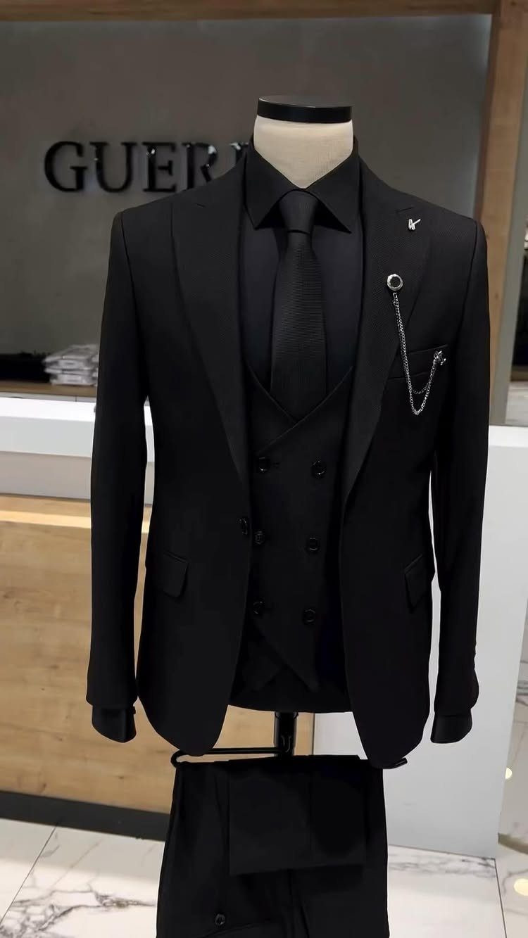 A black three-piece suit with a silver chain displayed on a mannequin.