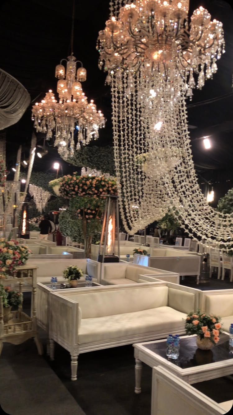 Crystal chandeliers and white sofas arranged in an elegant ballroom wedding reception setting.