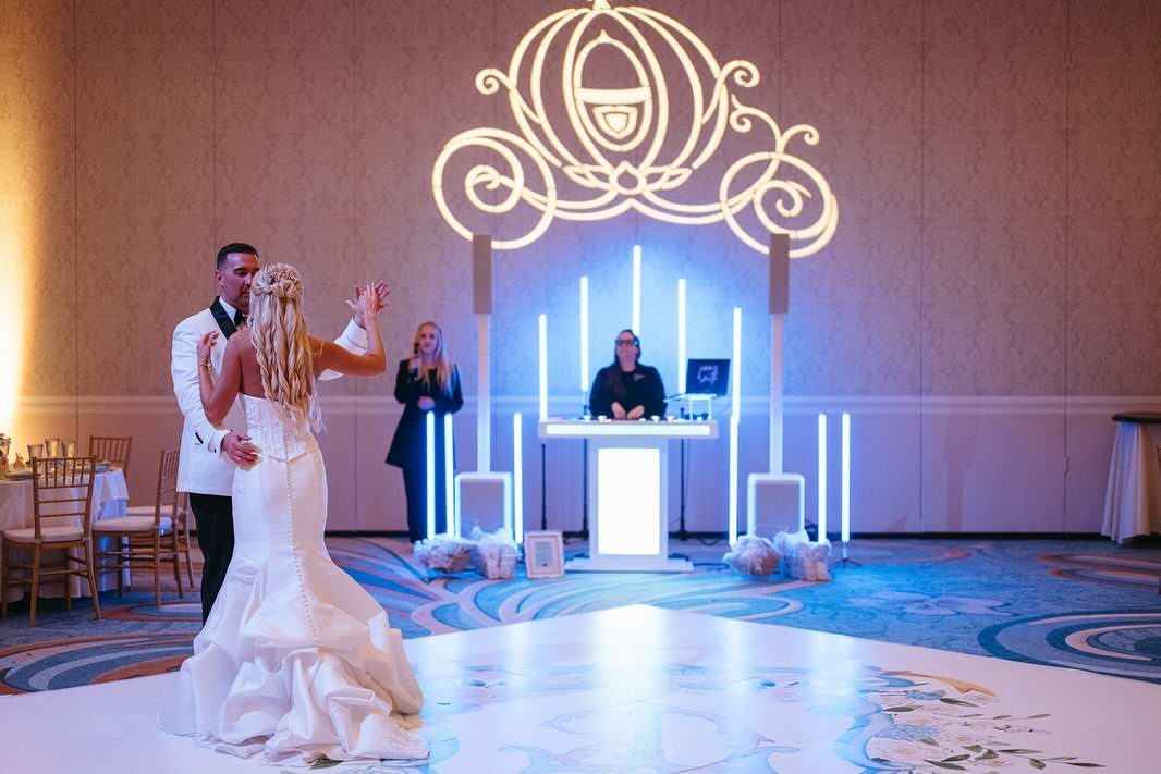 A bride and groom dancing on a glowing white dance floor during a wedding reception.