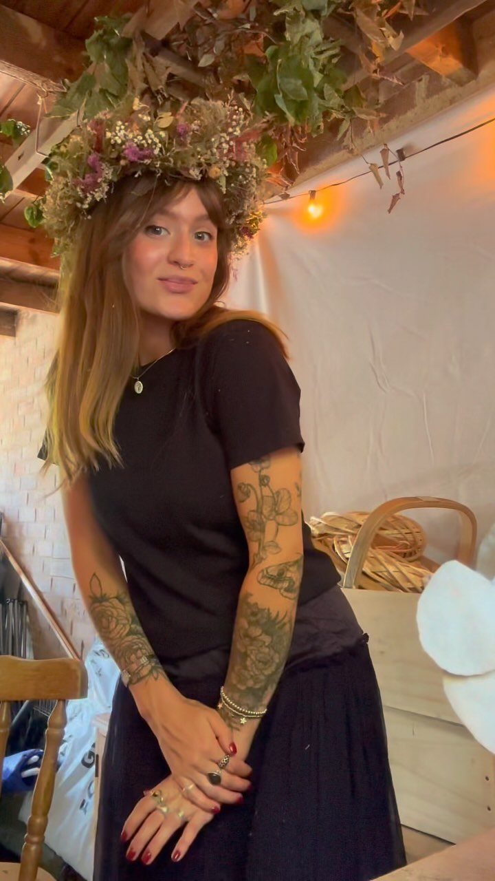 A woman with long brown hair wearing a crown of small dried flowers.