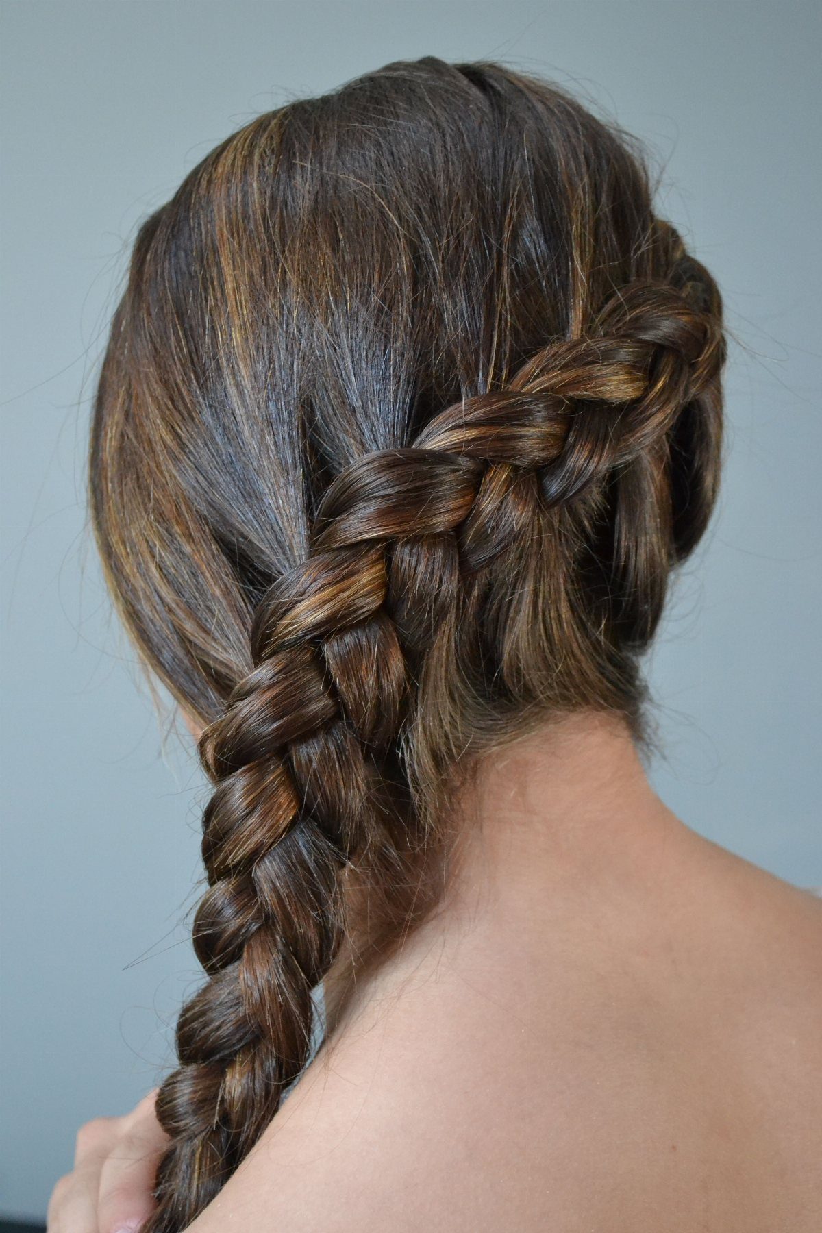 A thick, textured side Dutch braid in brunette hair viewed from behind.