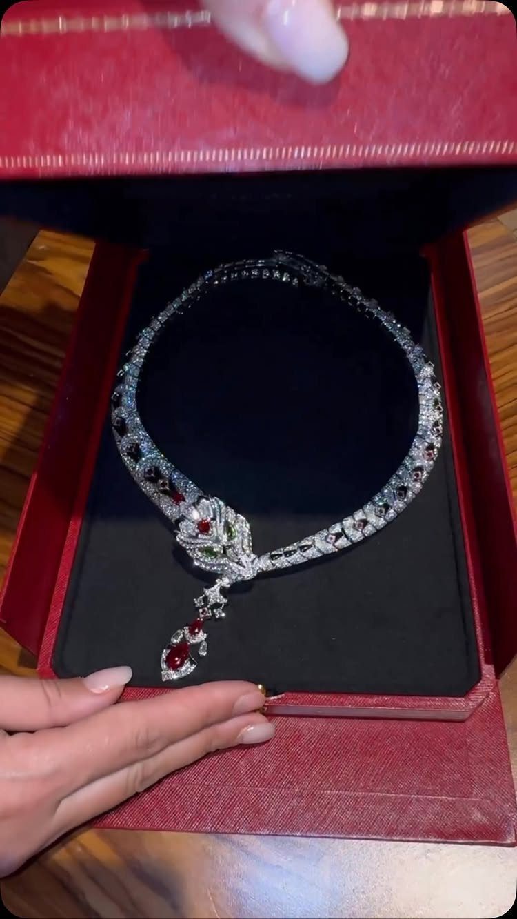 11 Bridal Diamond Necklace Ideas for Your Ceremony 10 A silver diamond necklace with red stones resting inside a red jewelry box.