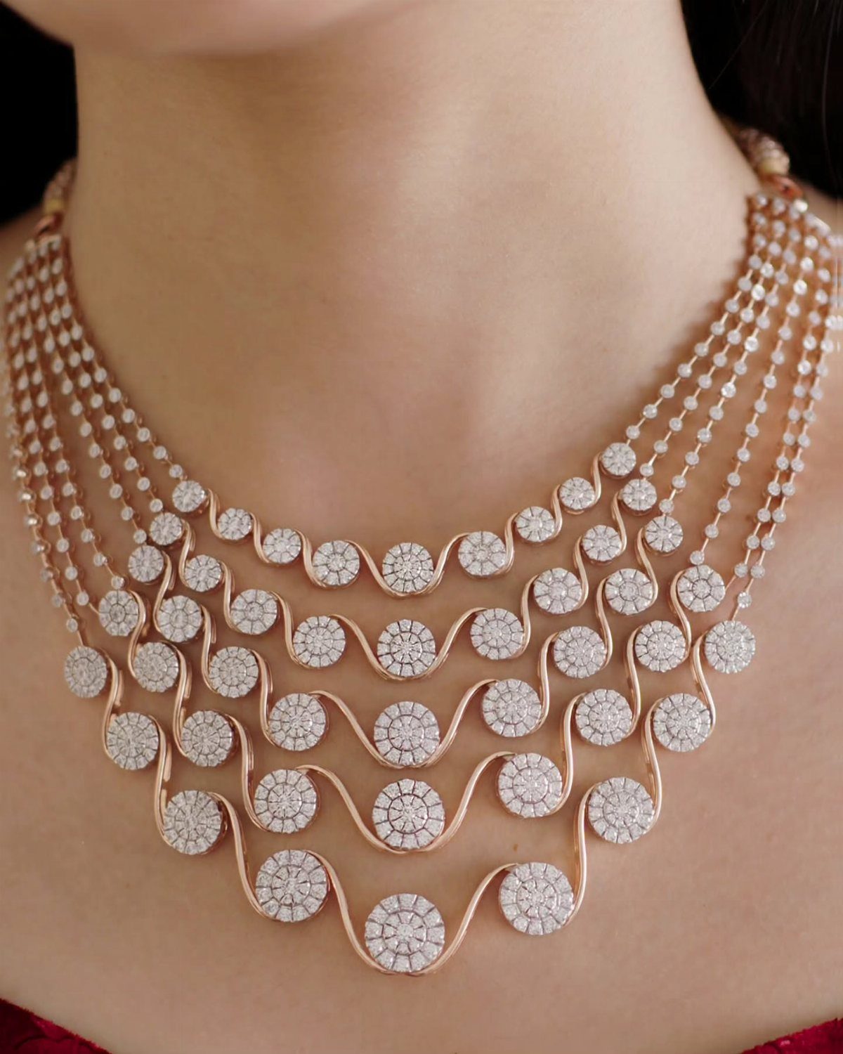 11 Bridal Diamond Necklace Ideas for Your Ceremony 6 A rose gold layered diamond necklace with wavy lines and circular diamond patterns on a person.