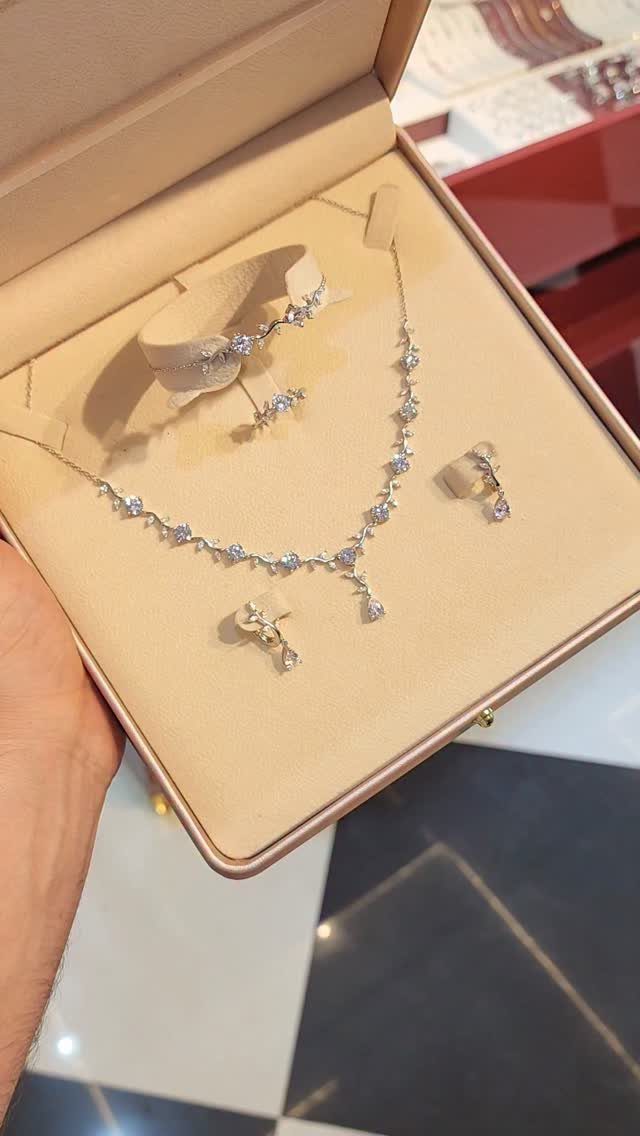 11 Bridal Diamond Necklace Ideas for Your Ceremony 9 A delicate silver diamond necklace and matching earrings displayed inside a beige jewelry box.