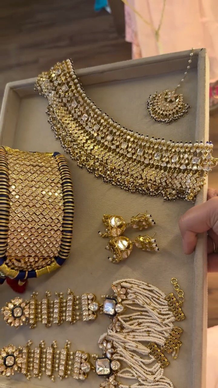 Gold-toned kundan jewelry set including a choker necklace, earrings, and bracelet on a tray.