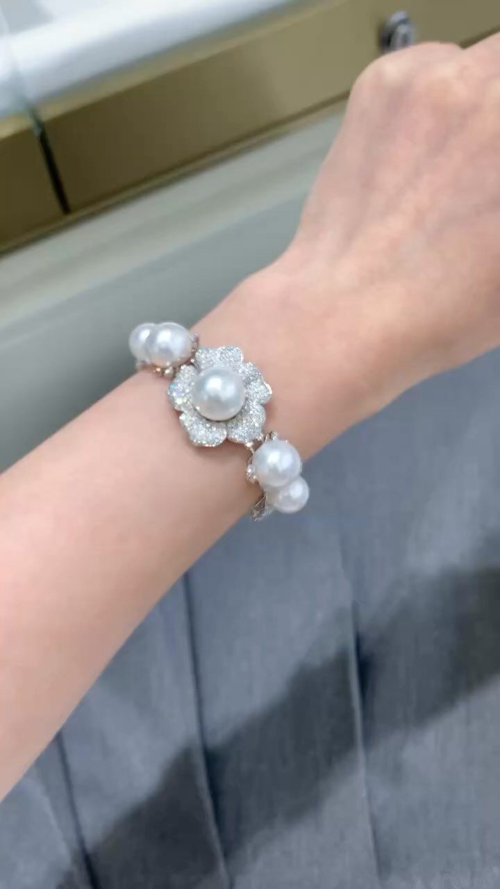 A silver rhinestone and pearl bracelet worn on a person's wrist.