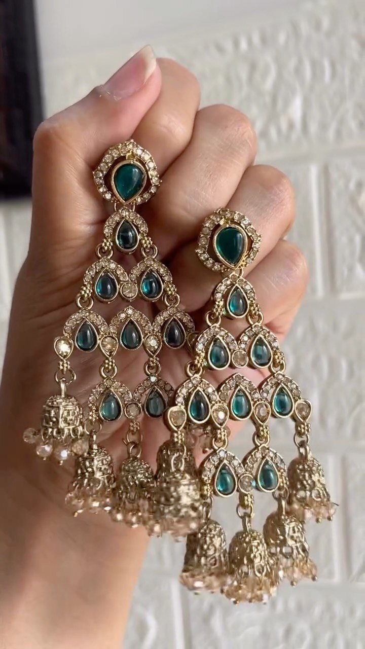 Bridesmaid Jewelry Gold: 10 Ideas for Every Wedding Style 3 A hand holding large gold teardrop earrings with teal stones and pearl bell charms.