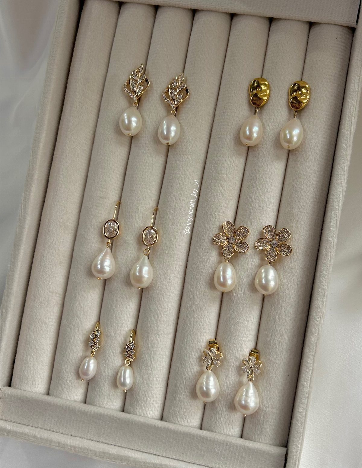 Bridesmaid Jewelry Gold: 10 Ideas for Every Wedding Style 10 Various gold pearl drop earrings displayed in a beige velvet jewelry organizer tray.