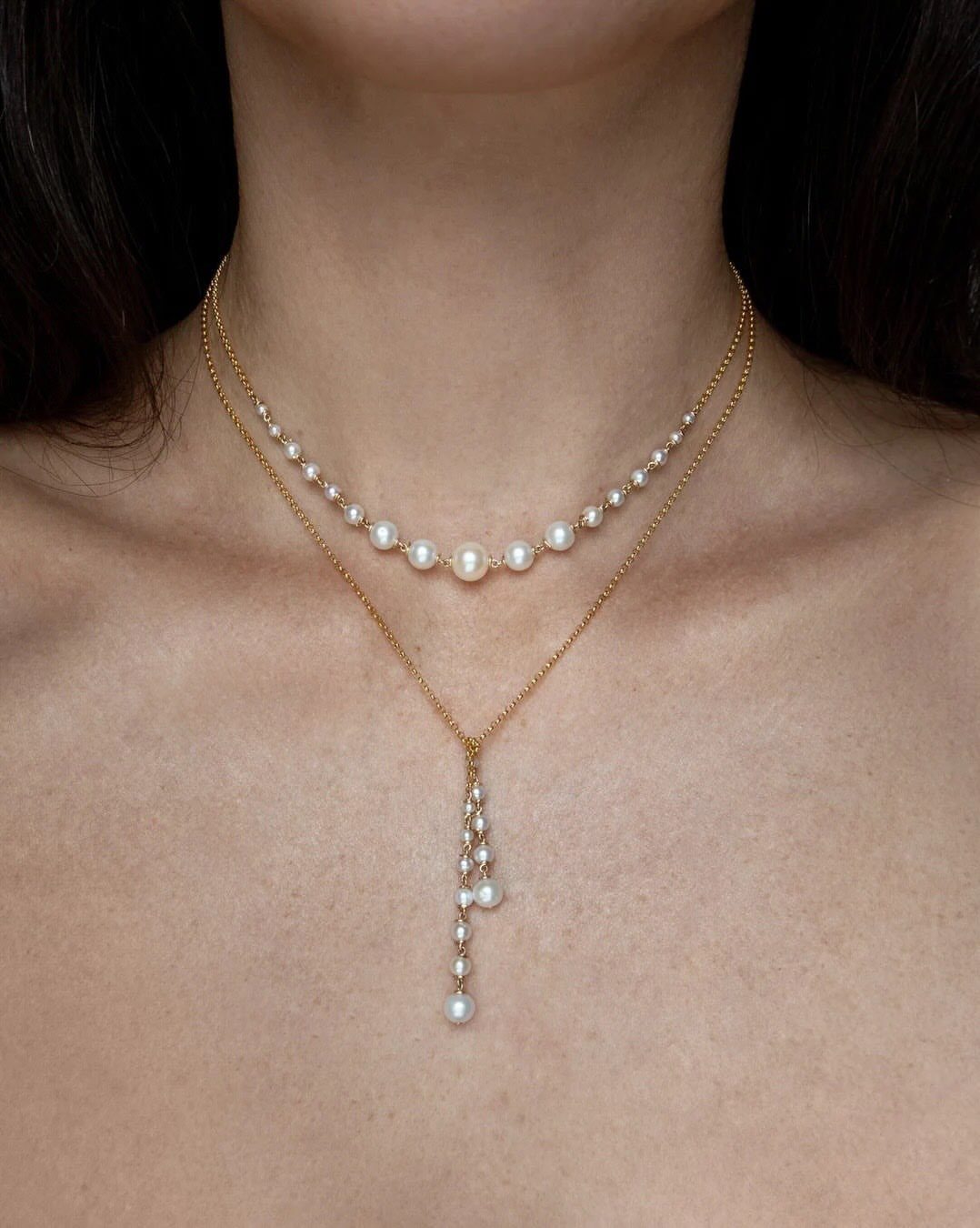 Bridesmaid Jewelry Gold: 10 Ideas for Every Wedding Style 6 A person wearing layered gold necklaces with white pearls on their neck.