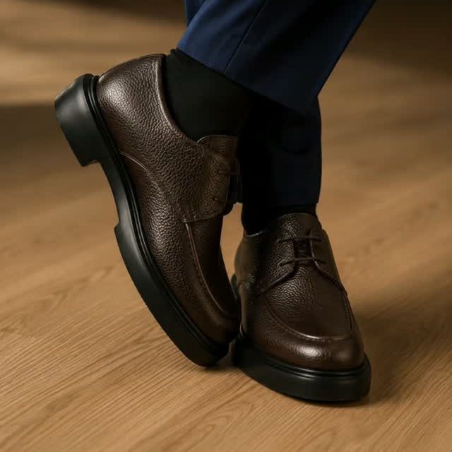 Dark brown pebbled leather derby shoes with thick black soles worn with navy trousers.