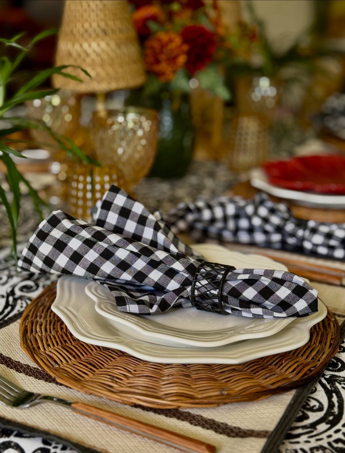 Black and white gingham napkin on white plates and a brown woven charger plate.