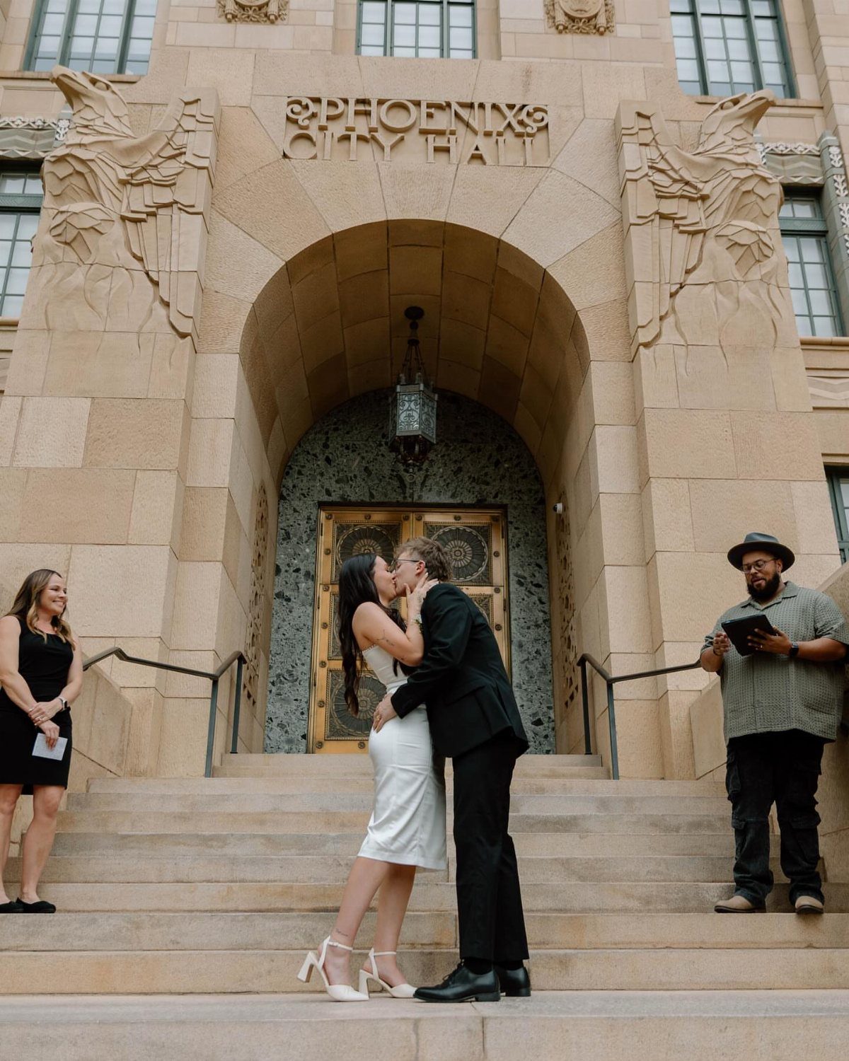A bride and groom kissing on the stone steps in front of Phoenix City Hall.