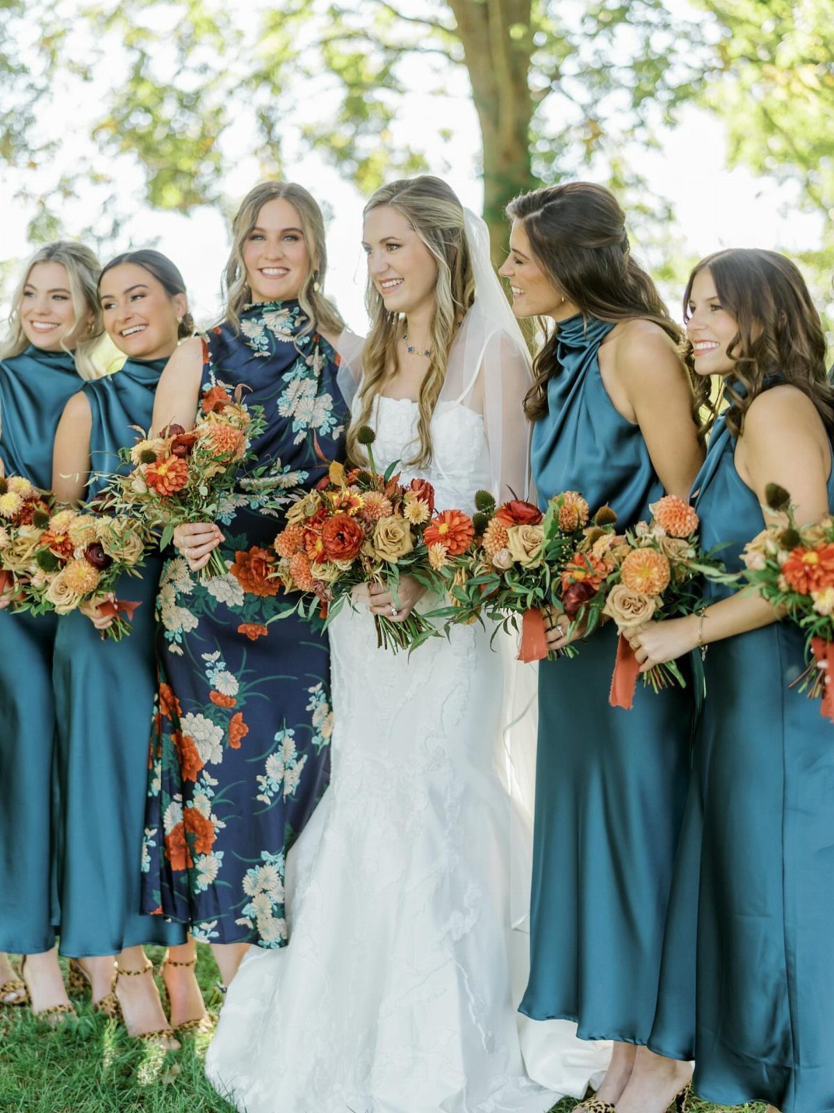 9 Earth Tone Wedding Colors That Feel Grounded, Not Dull 9 Bridesmaids in teal dresses holding warm-toned floral bouquets standing with a bride.