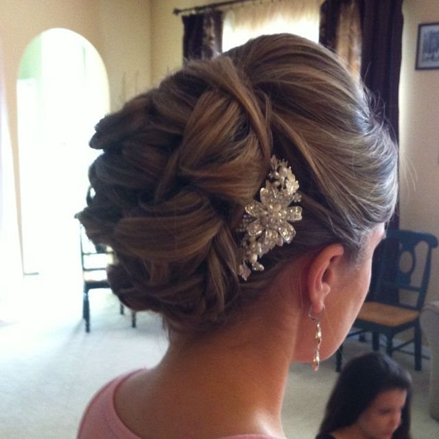 A woman's hair styled in an intricate braided updo with a silver floral accessory.