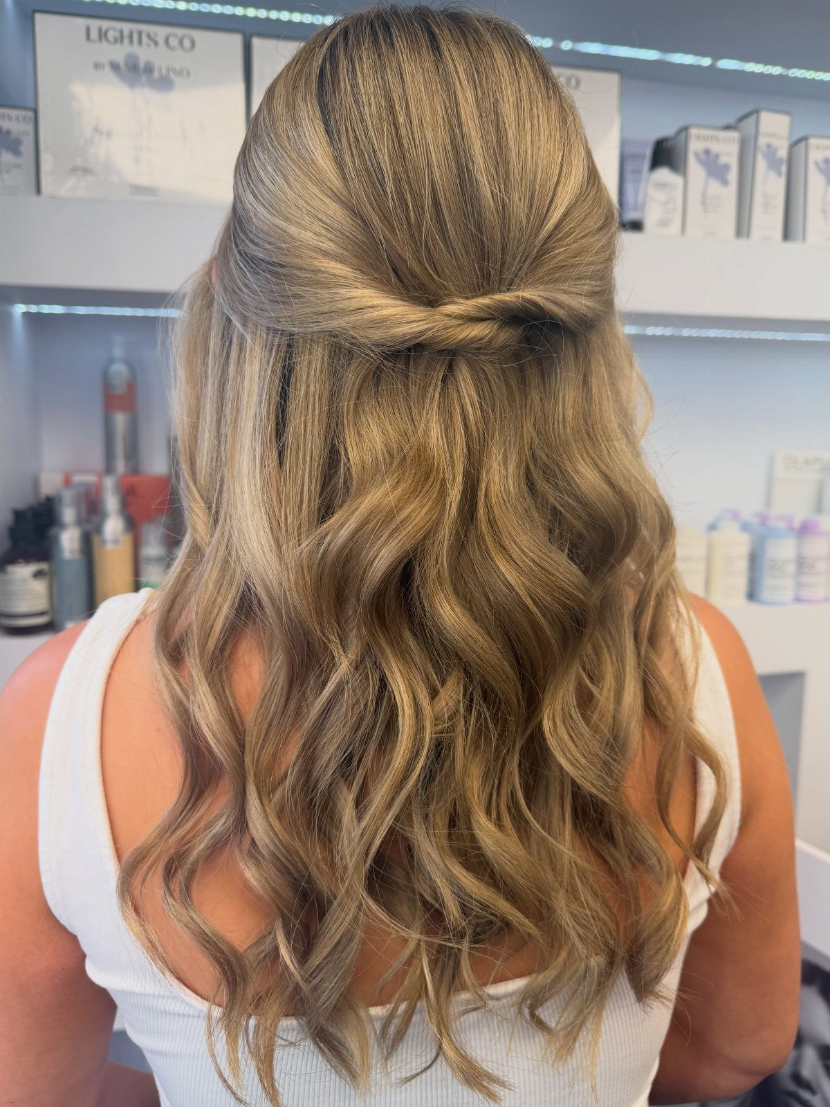 Long blonde hair styled in a half-up fashion with soft cascading curls.