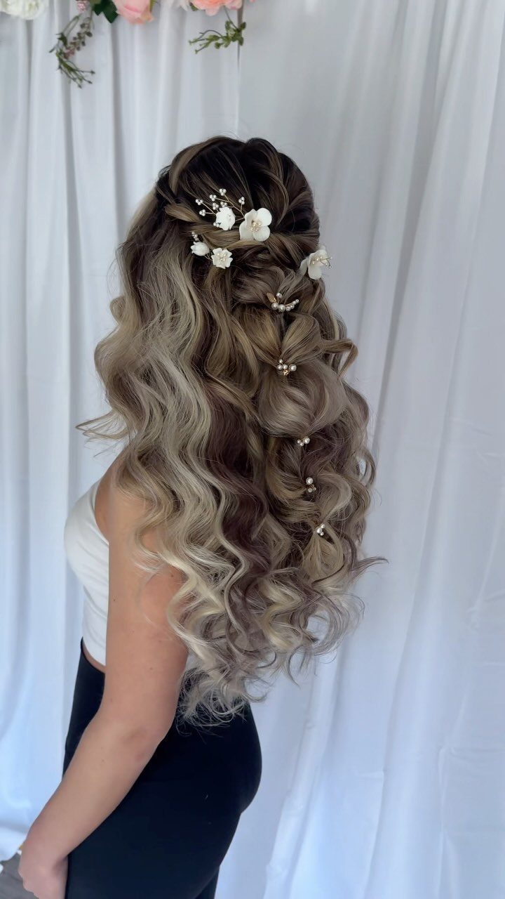 Long wavy hair decorated with small white floral hair accessories against a white curtain background.