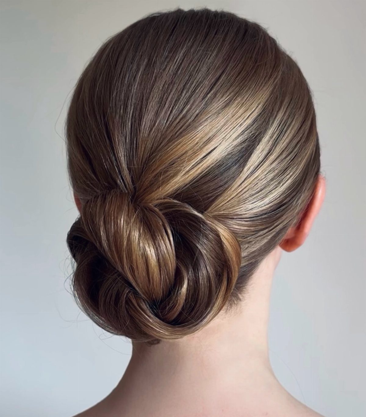 A person with light brown hair styled in a sleek, polished low bun.