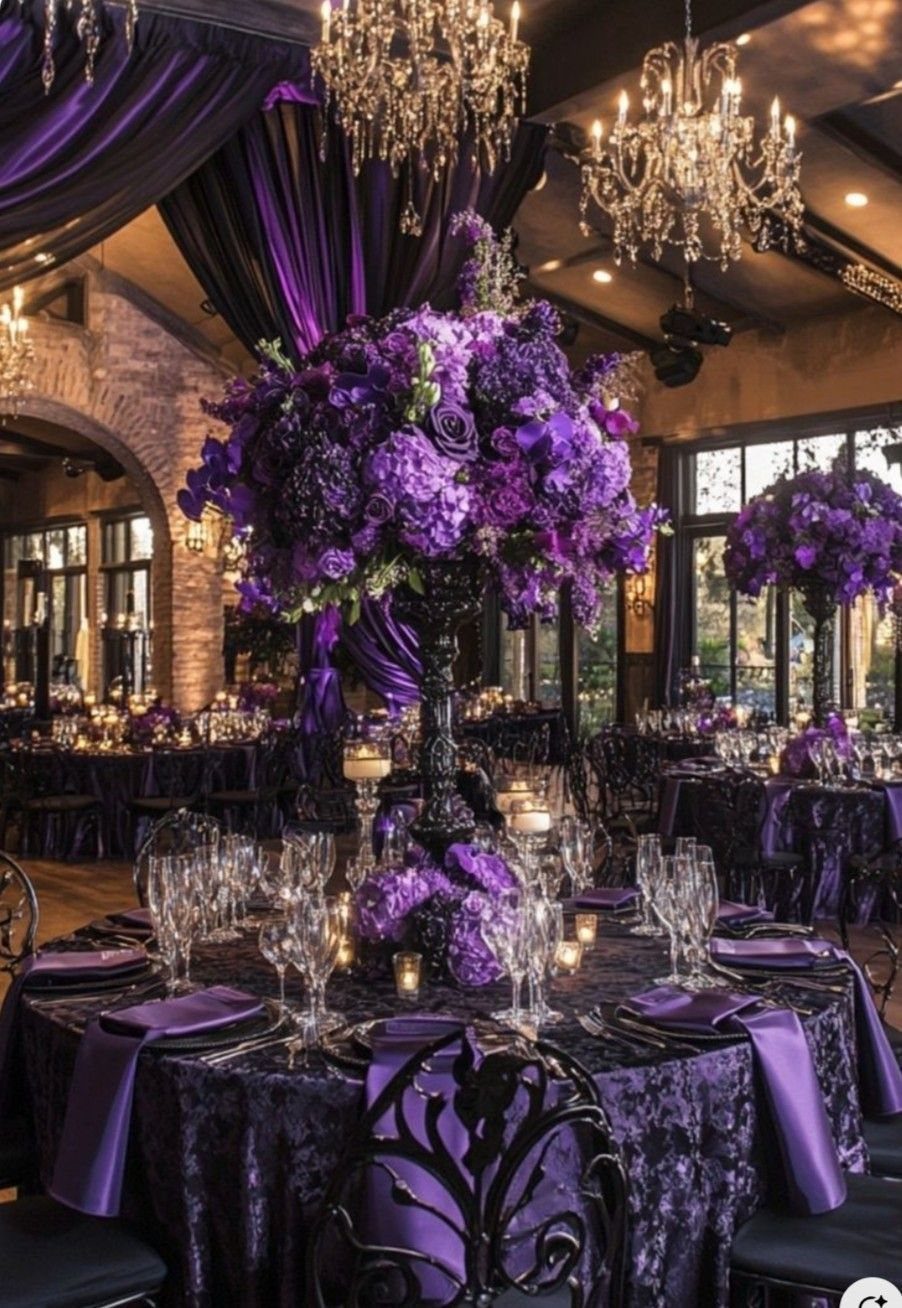 Purple floral centerpieces on velvet tablecloths at a formal wedding reception with crystal chandeliers.