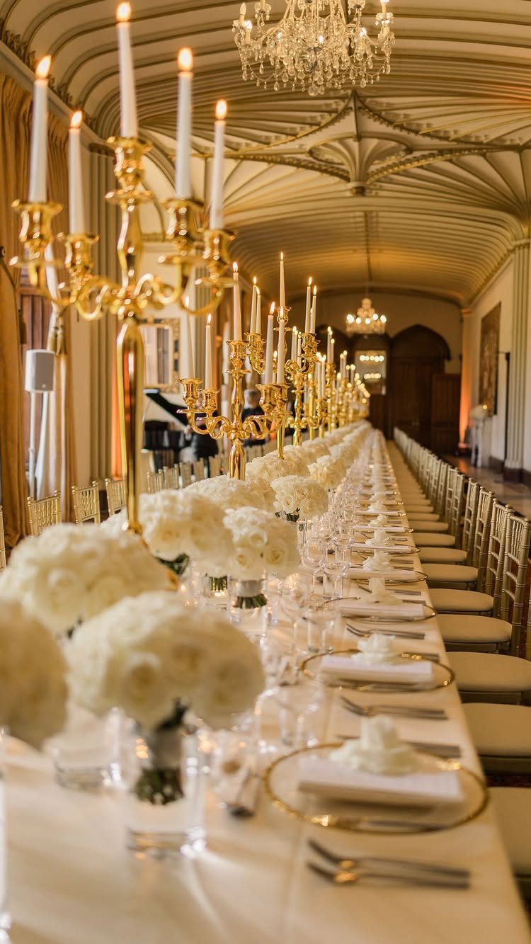 Gold candelabras with white candles line a long banquet table with white roses.