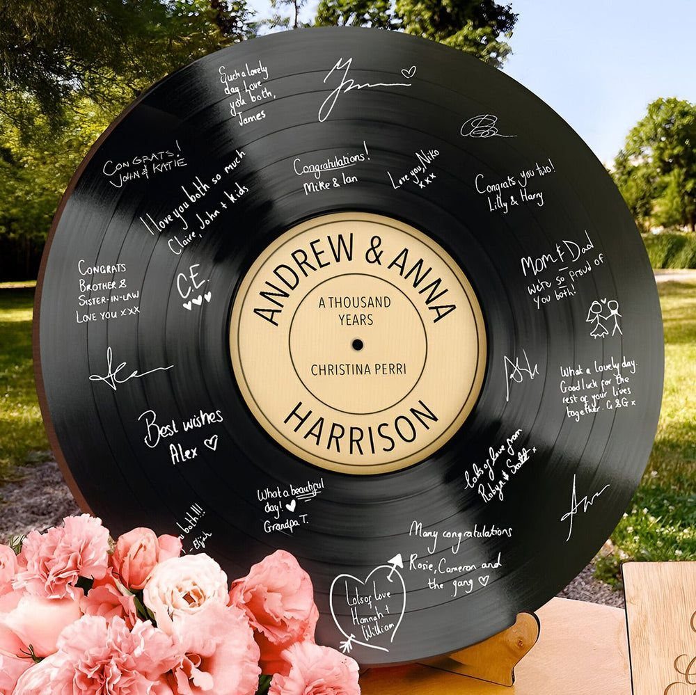 A black vinyl record covered in white handwritten wedding guest signatures and messages.