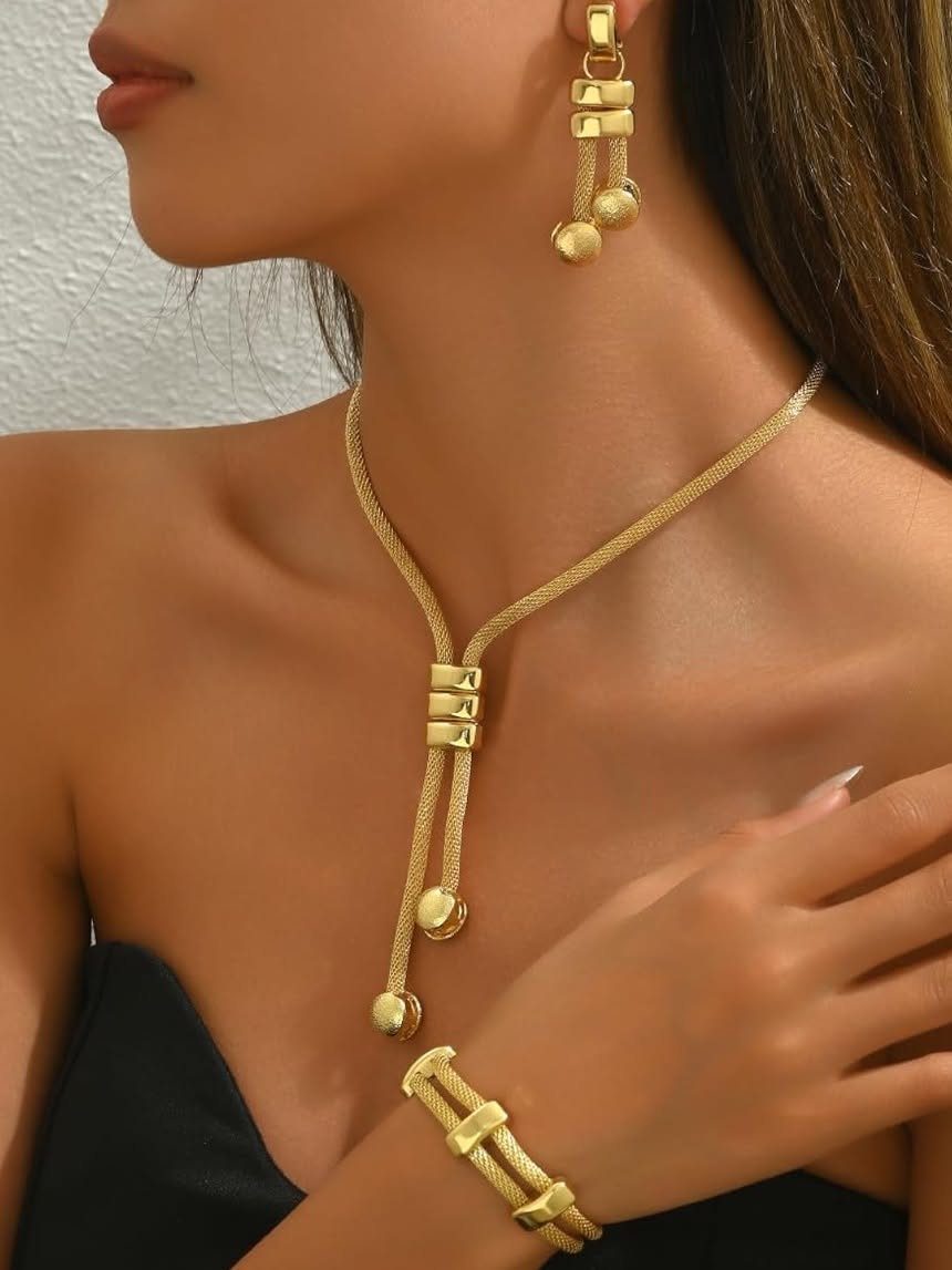 A person wearing a matching gold-toned necklace, bracelet, and drop earrings set.