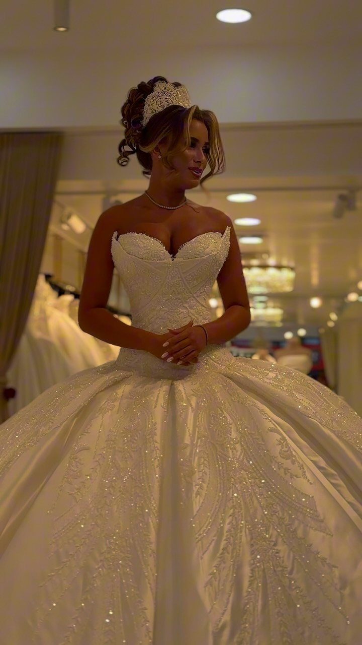Woman in a white strapless ball gown with a voluminous shimmering skirt and tiara.