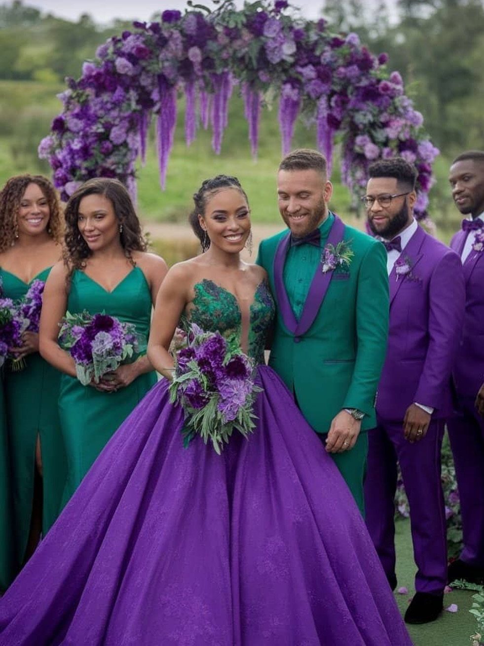 Wedding party posing in vibrant emerald green and deep purple formal attire outdoors.