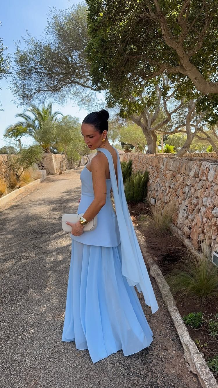 Light Blue Wedding: 8 Ideas From Cake to Tulle Runner 2 A woman in a long light blue sleeveless gown standing on a path outdoors.