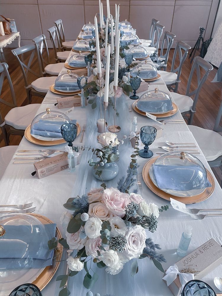 Light Blue Wedding: 8 Ideas From Cake to Tulle Runner 8 A long wedding table decorated with a light blue tulle runner, blue glassware, and white floral arrangements.