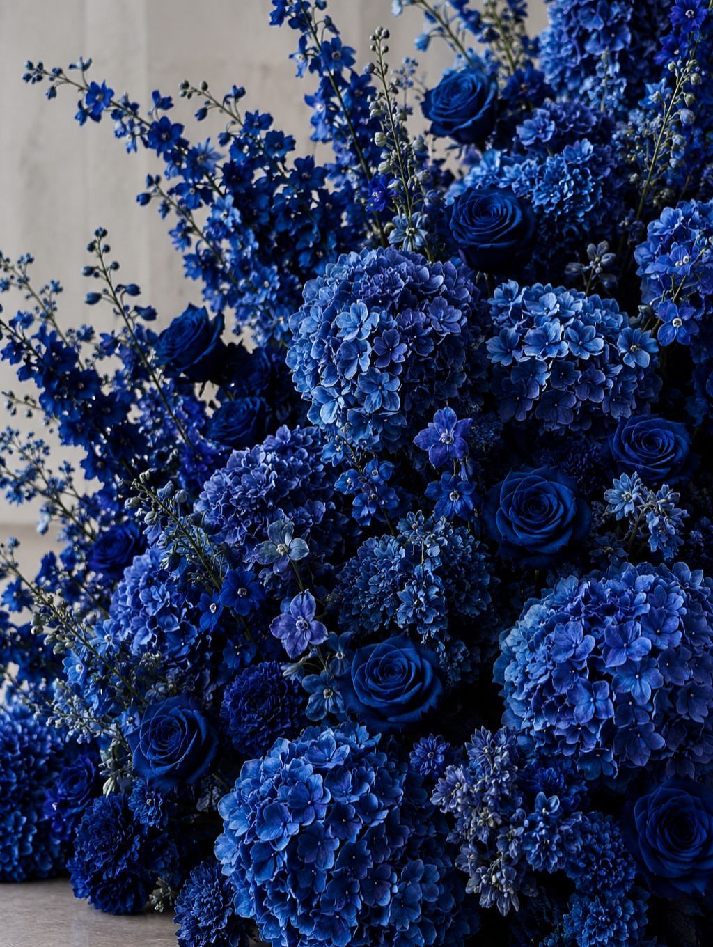 A lush arrangement of various blue flowers including roses and hydrangeas in deep navy tones.
