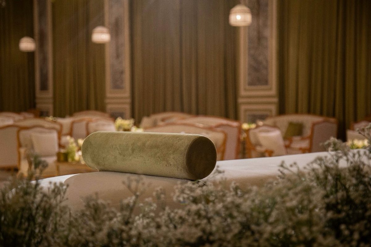 Olive green drapes hanging behind white armchairs in a decorated lounge area.