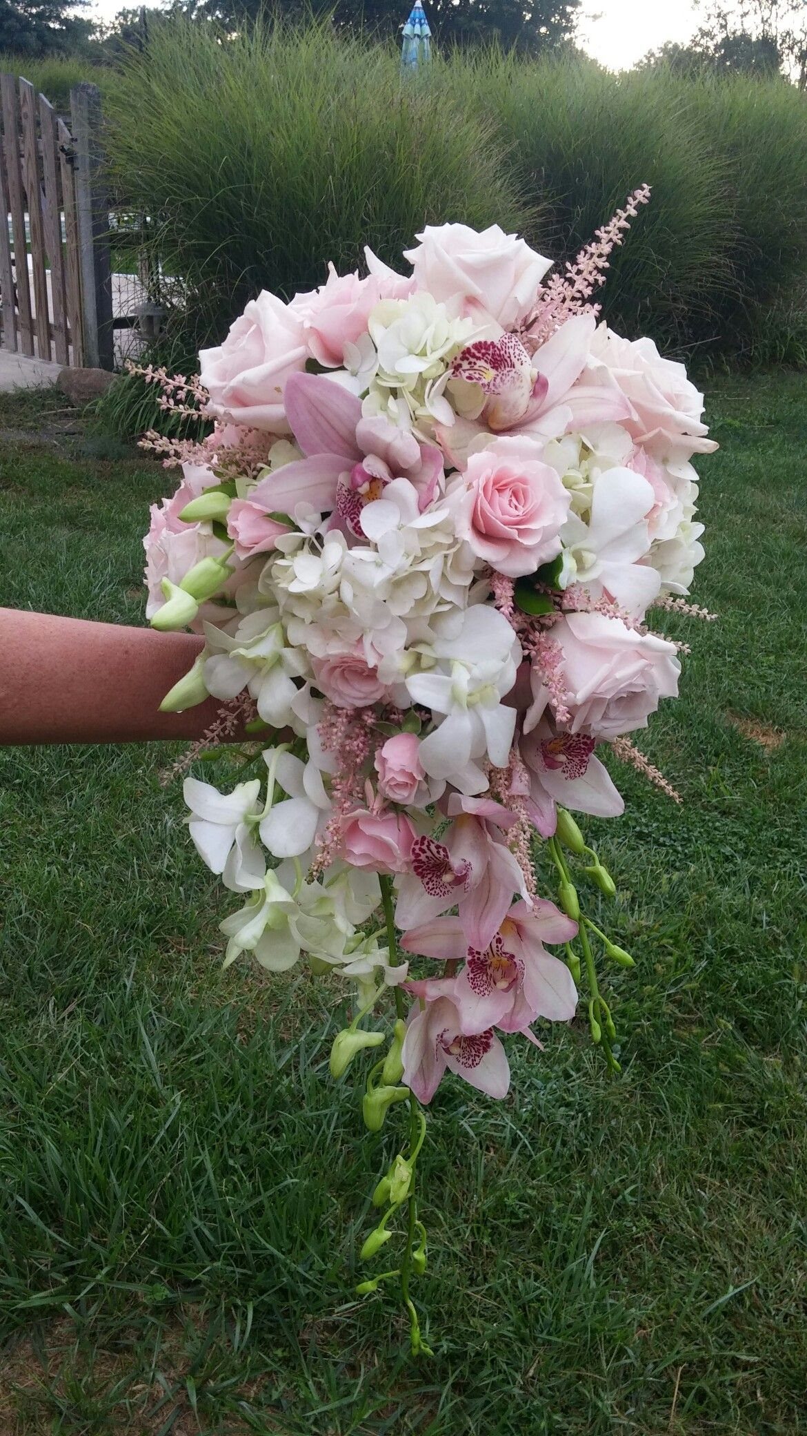 7 Orchids Bouquet Wedding Ideas for Every Style of Ceremony 5 A cascading wedding bouquet with pink roses, white hydrangeas, and various pink and white orchids.