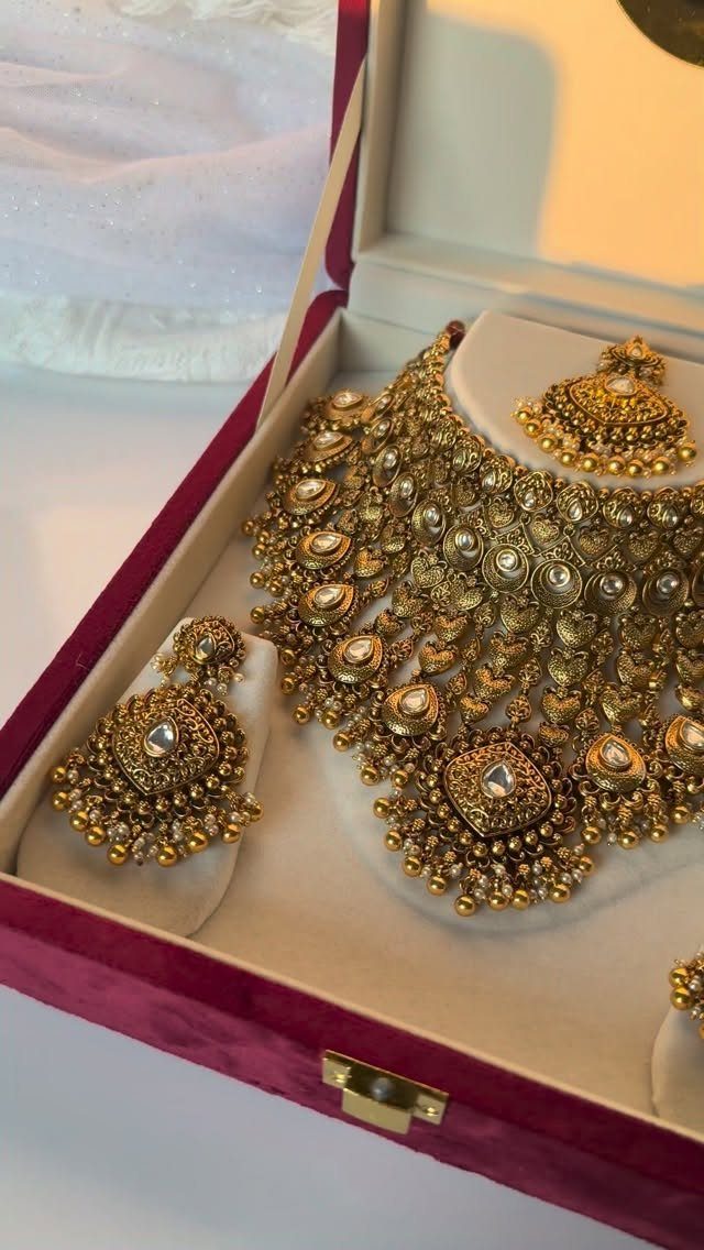 Intricate gold antique necklace and matching earrings displayed in a velvet jewelry box.