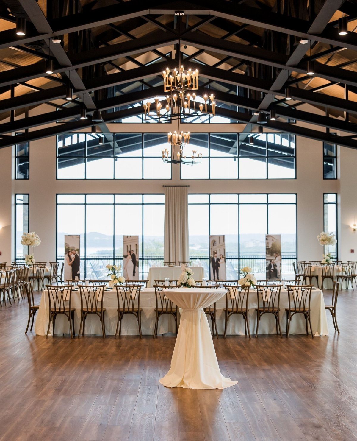 An elegant banquet hall with high ceilings, large windows, and long dining tables set for a reception.