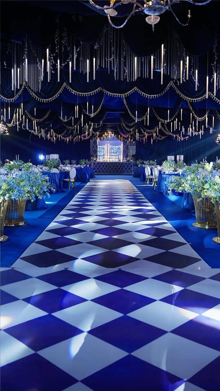 A blue and white checkered aisle runner stretching through a decorated wedding reception hall.