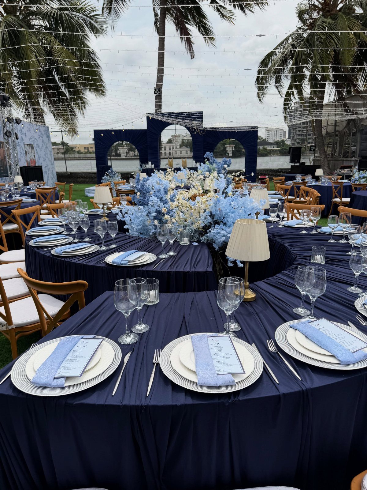 Round dining tables decorated with royal blue tablecloths, light blue floral centerpieces, and elegant place settings.