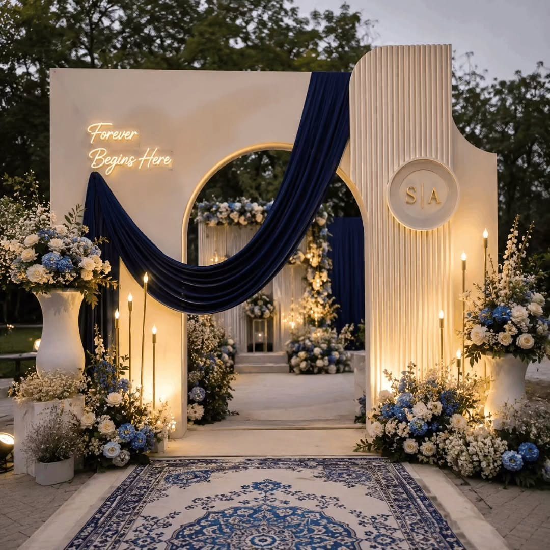 White wedding arch with royal blue drapes and blue and white floral arrangements.