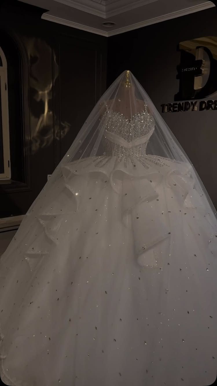 A white wedding dress with a sparkling bodice and large ruffles displayed on a mannequin.