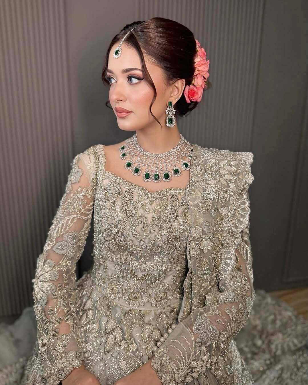 5 Silver Necklace Wedding Looks for Every Bridal Style 5 A woman in silver bridal attire wearing a green gemstone necklace and matching jewelry.