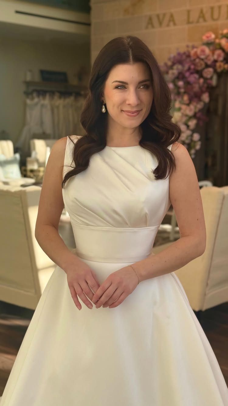 Simple Court Wedding Dress: 7 Styles That Work at City Hall 2 A woman posing in a sleeveless white satin A-line wedding dress with a wide waistband.