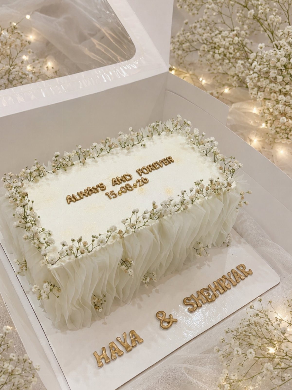 13 Wedding Cakes with Flowers to Suit Every Style 9 White rectangular wedding cake decorated with tiny white baby's breath flowers and gold lettering.