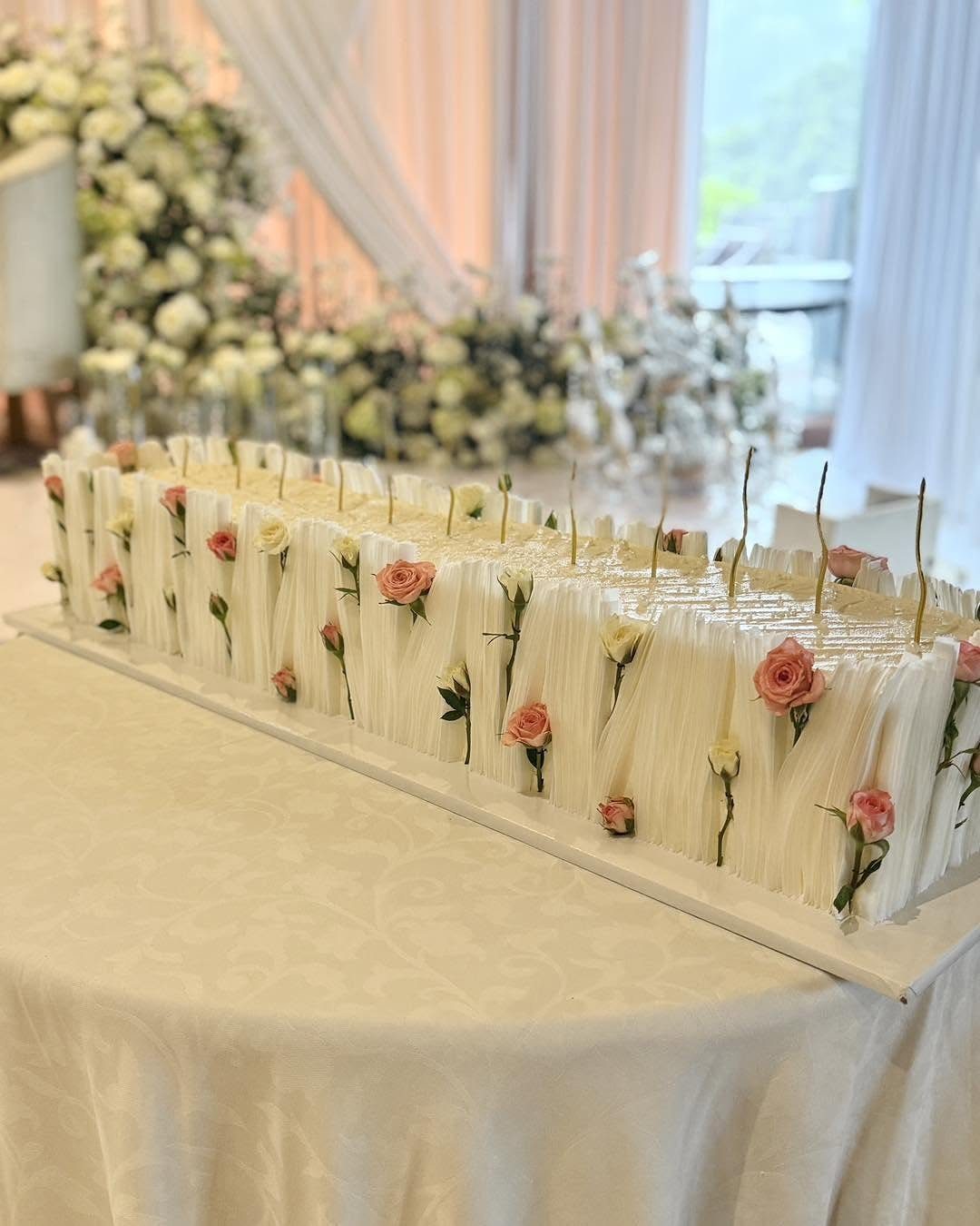 13 Wedding Cakes with Flowers to Suit Every Style 6 Small white rectangular cakes decorated with scattered pink and cream rosebuds on a white tablecloth.