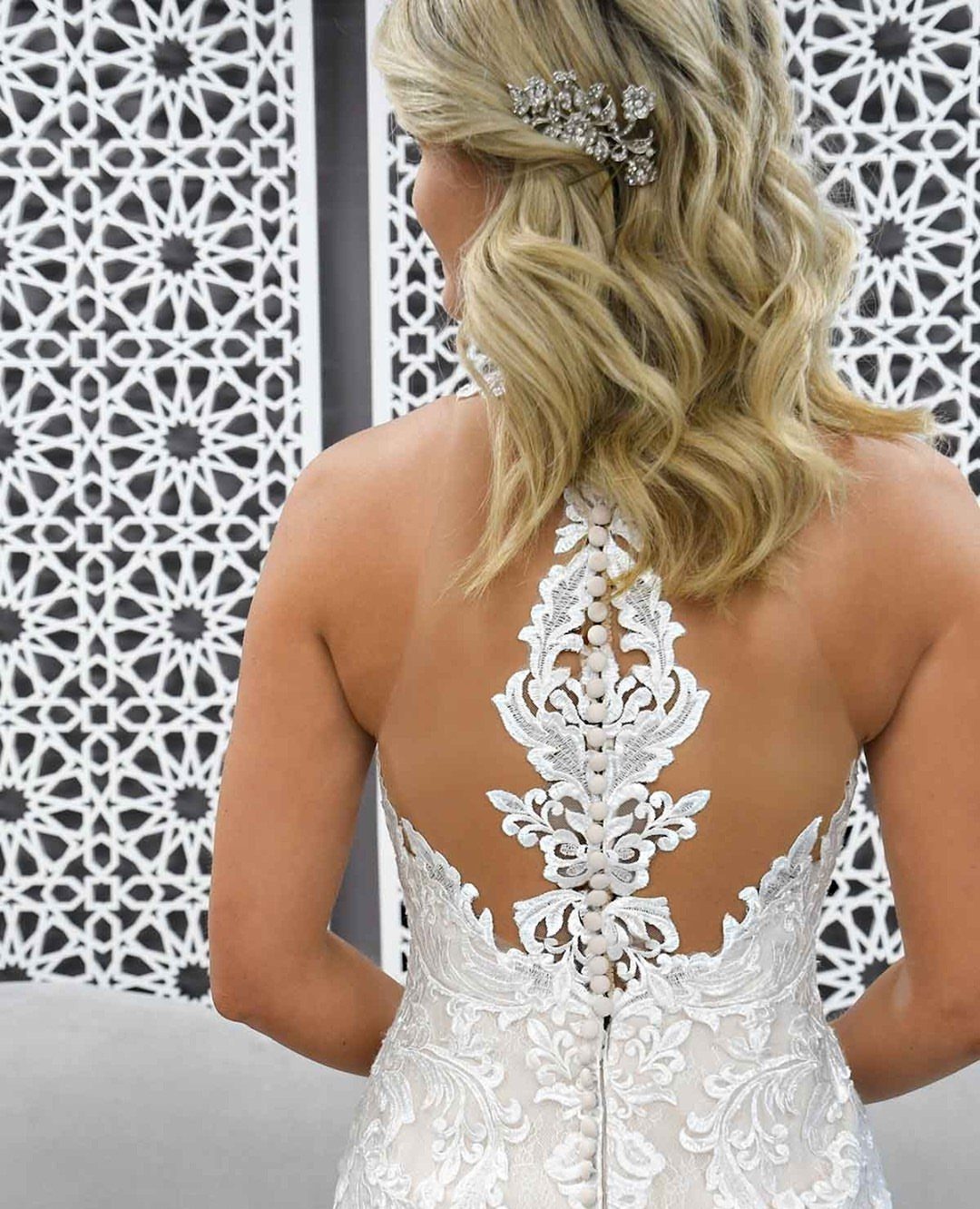 Wedding Dress Backs: 10 Styles That Turn the Exit Into a Moment 2 Woman wearing a white lace wedding dress with an intricate illusion back and button details.