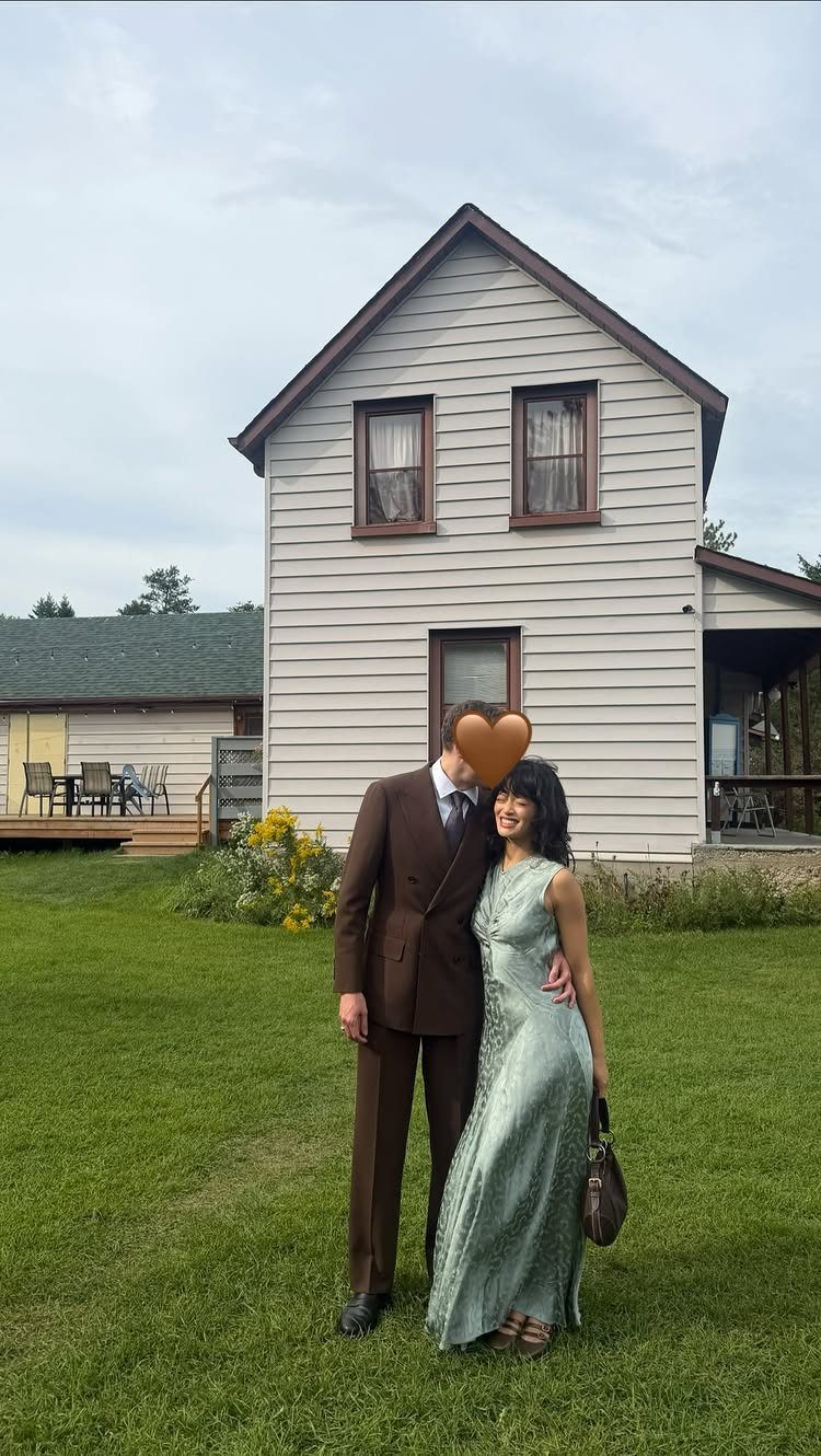 A man in a brown suit and a woman in a light blue gown standing on grass.