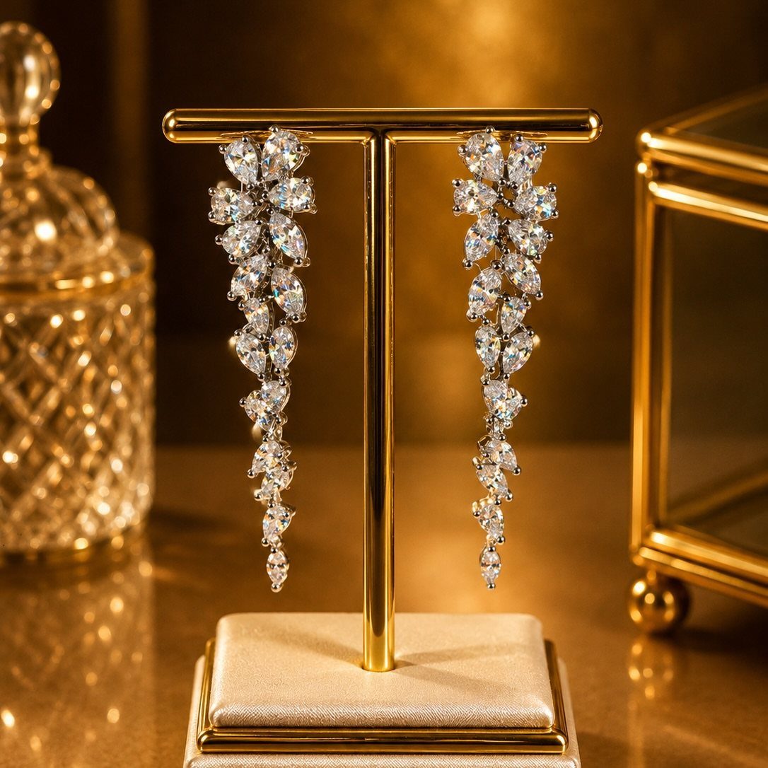 Long silver chandelier earrings with teardrop crystals displayed on a gold jewelry stand.
