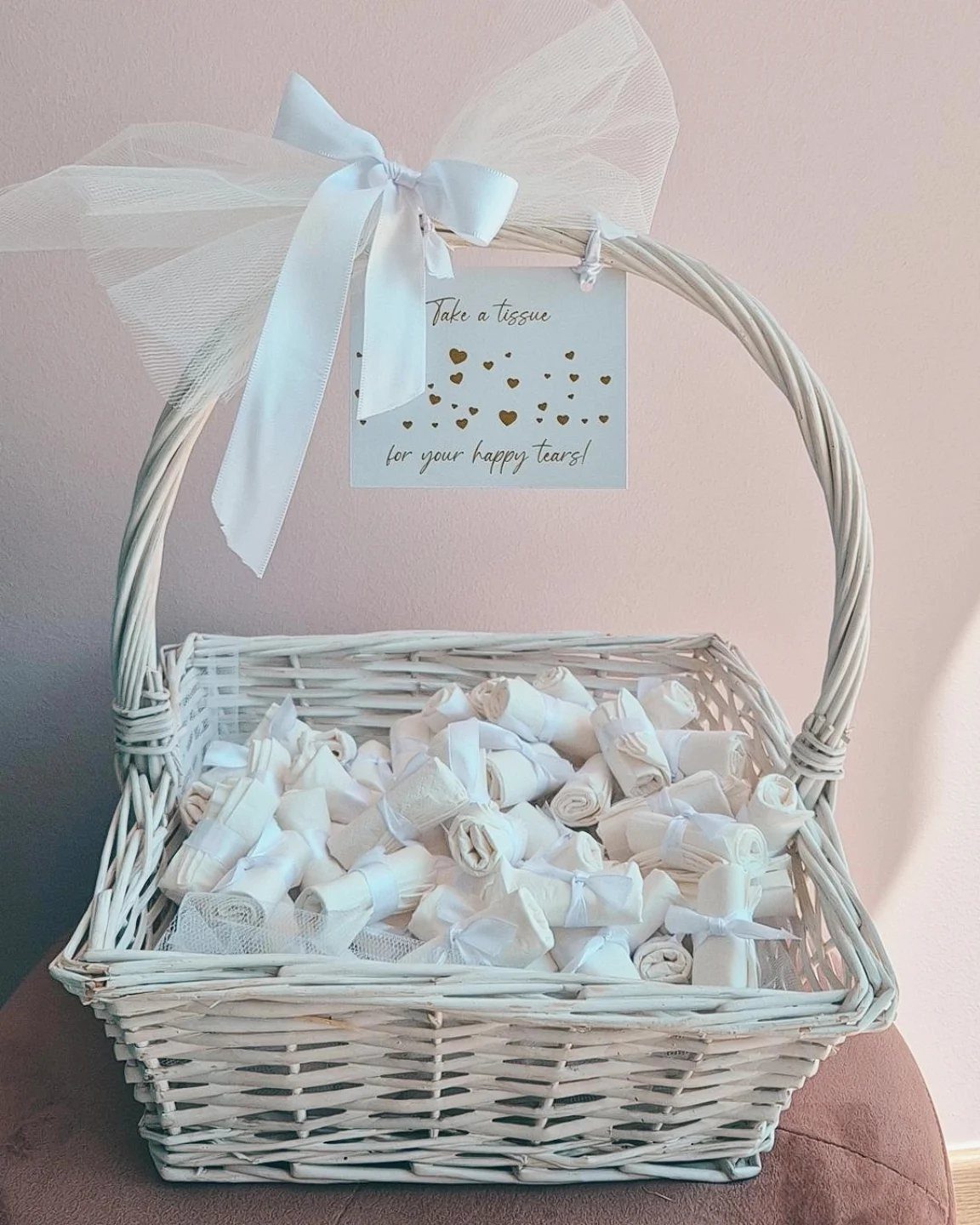 10 Wedding Favors for Guests Ideas: From Plants to Hot Sauce 8 White wicker basket filled with small rolled white tissues and a sentimental hanging card.