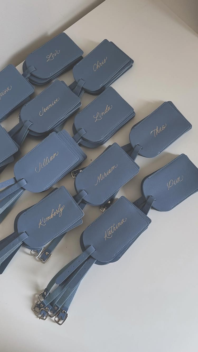 10 Wedding Favors for Guests Ideas: From Plants to Hot Sauce 2 Blue leather luggage tags with gold names arranged on a white surface.
