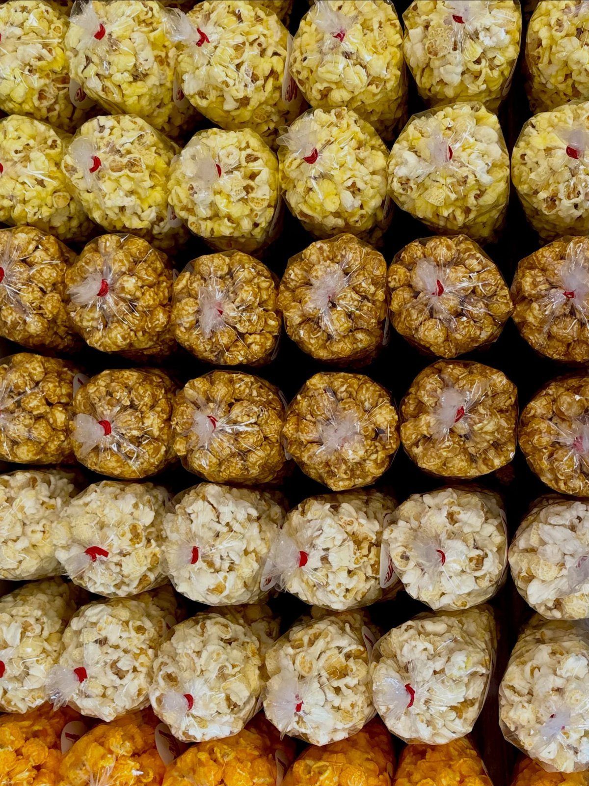 Rows of small clear plastic bags filled with various flavored popcorn.