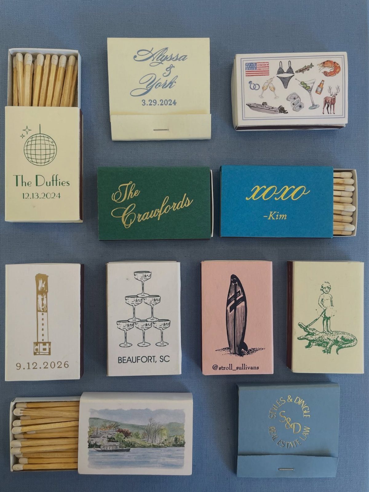 Multiple personalized matchbooks with various designs, colors, and custom names laid out on a blue background.